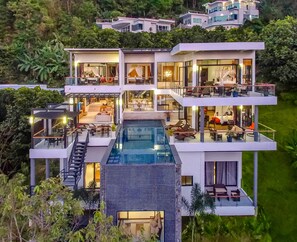 A multi-story modern house with a large pool, multiple balconies, and lush greenery surrounding it. - SHA Extra Plus Grand Villa Luxury Time (Choeng Thale)