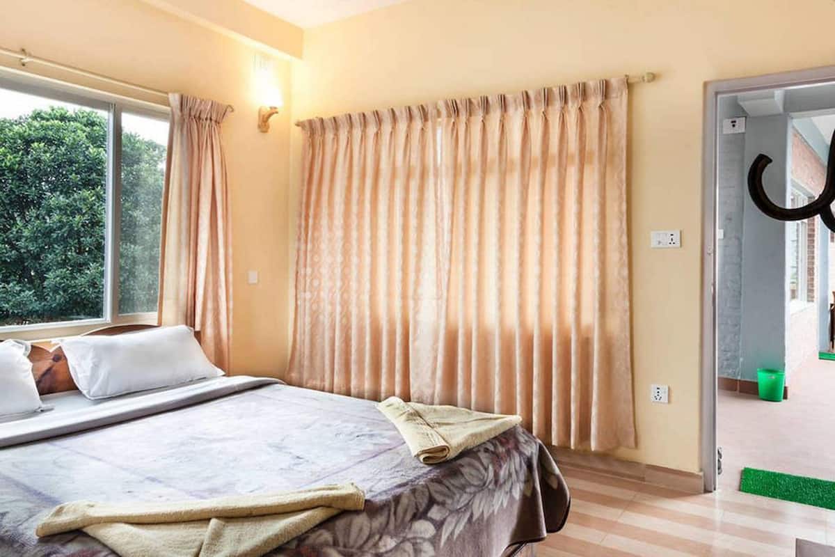 Une chambre à coucher avec un lit, des rideaux et une vue sur la verdure.