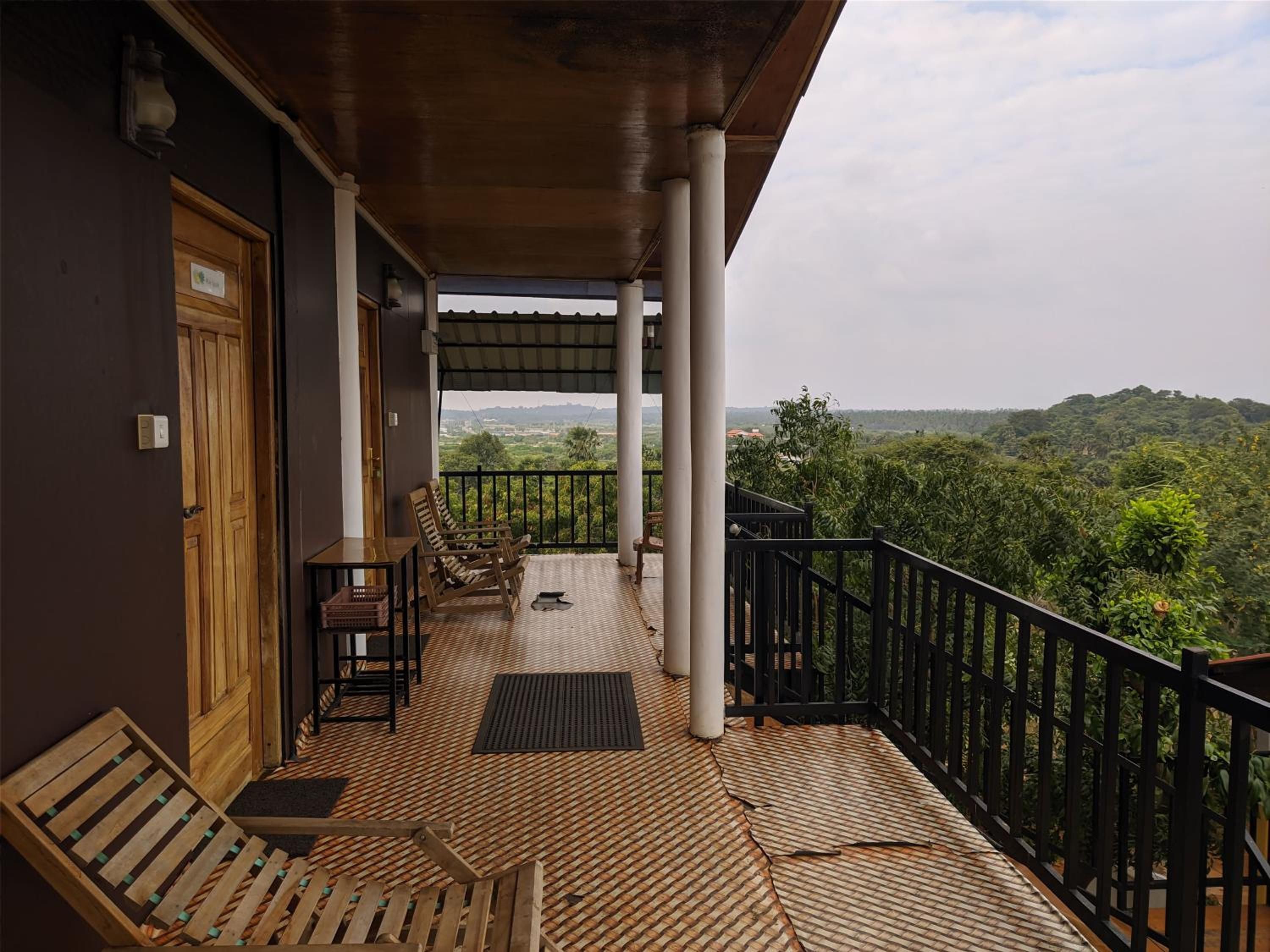 A balcony with wooden furniture, a view of the landscape, and a railing.