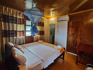A room with a bed, curtains, an air conditioning unit, and a wooden door.