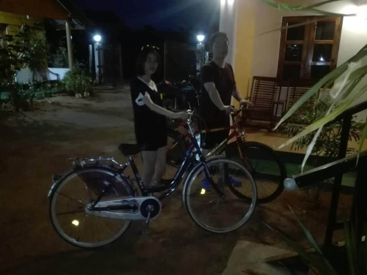 Two people standing next to a bicycle in an outdoor setting at night.