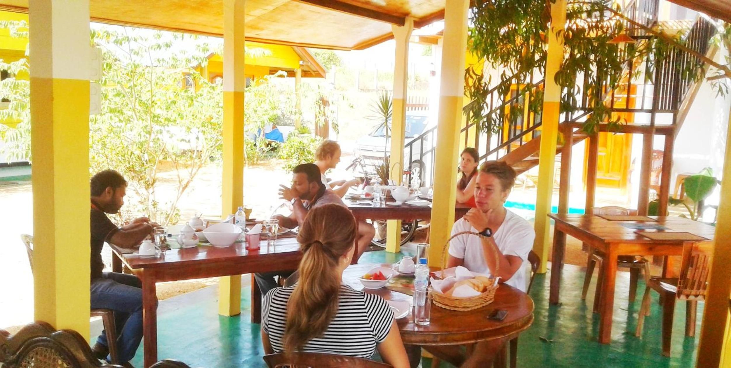 Een restaurant met terras, overdekt en omringd door groen.