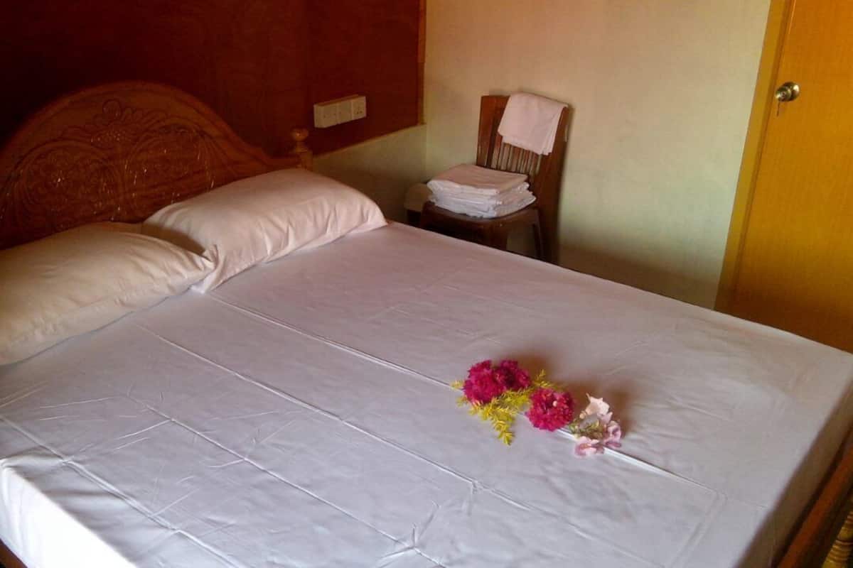 A neatly made bed with white linens and a bouquet of flowers on the bed.