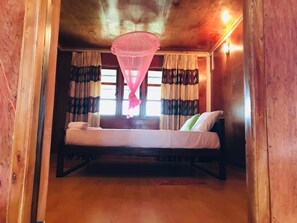 A room with a bed, a window with curtains, and a hanging mosquito net. - Sunntop Cabana (Trincomalee)