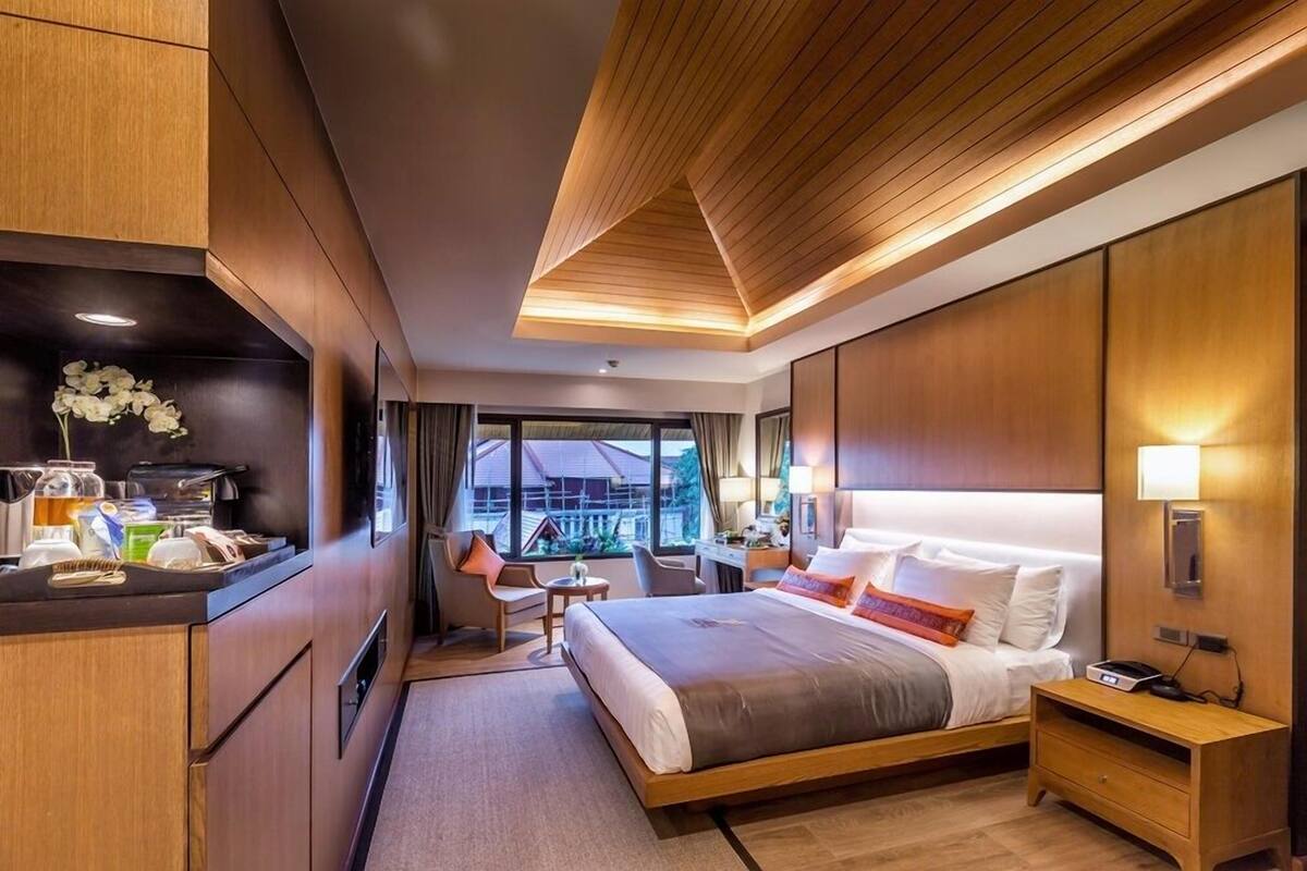 Habitación de hotel moderna con una cama grande, un escritorio, una silla y vistas al exterior.