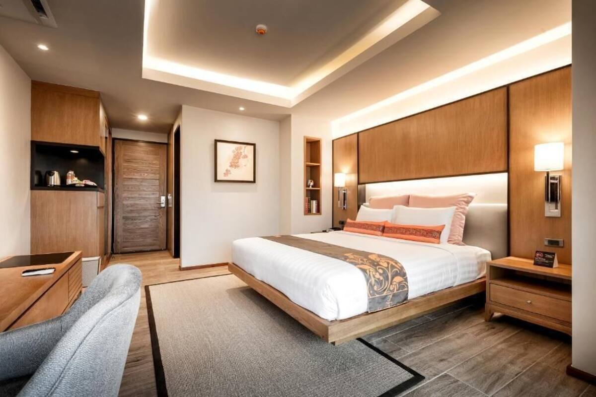Una habitación de hotel moderna con cama, mesitas de noche, escritorio y armario.