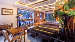 Un restaurant avec des tables et des chaises en bois, un plafond décoratif et une vue sur l’extérieur.