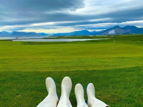 A golf course with a view of mountains and a cloudy sky.