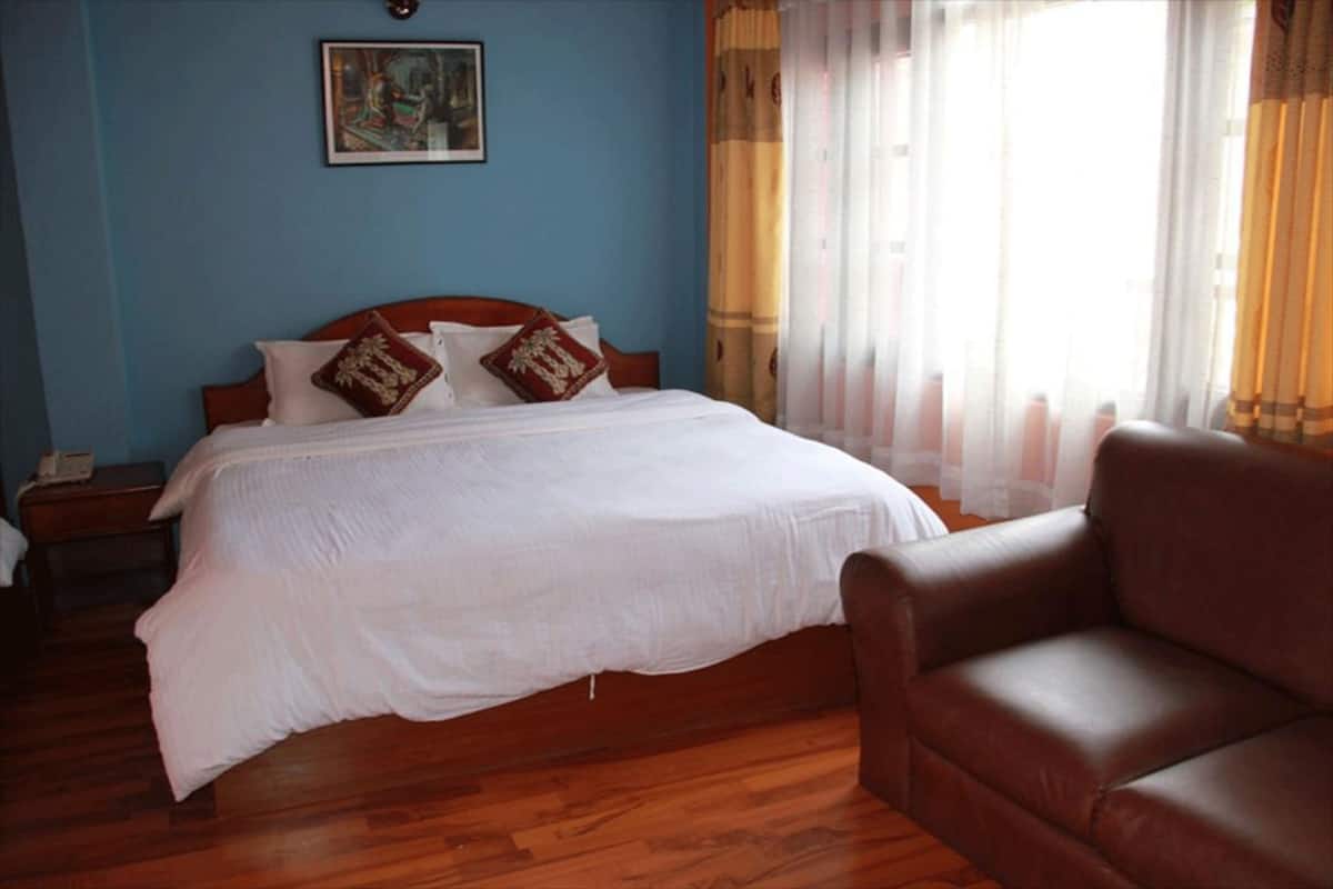 Ein Schlafzimmer mit einem Bett, einem Nachttisch, einem braunen Ledersessel und einem Bild an der Wand.