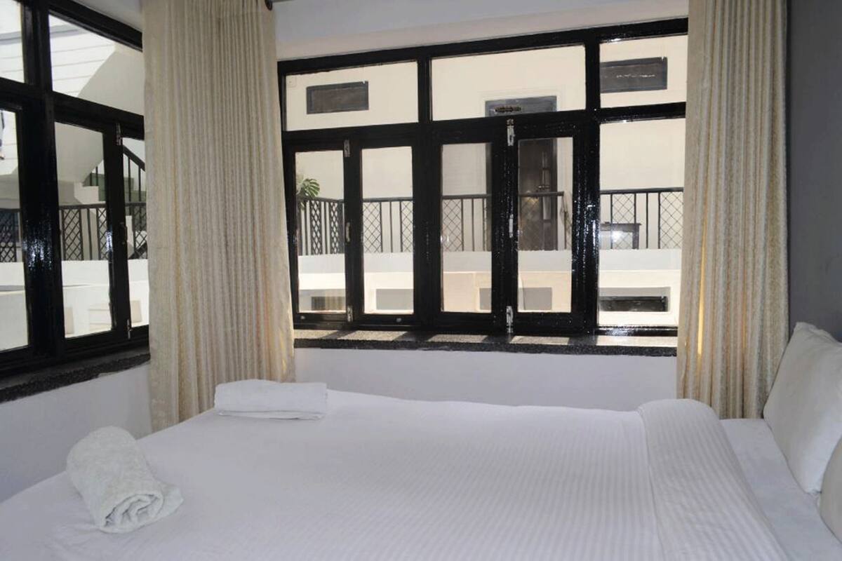 Ein Hotelzimmer mit einem großen Bett, einem Fenster mit Blick nach außen und einem Balkon.