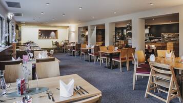 Ein geräumiges Restaurant mit mehreren Tischen, Stühlen, einer Theke und einer Auswahl an Speisen.