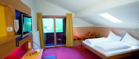 Habitación de hotel con cama, televisor, escritorio y ordenador, y vistas al exterior.