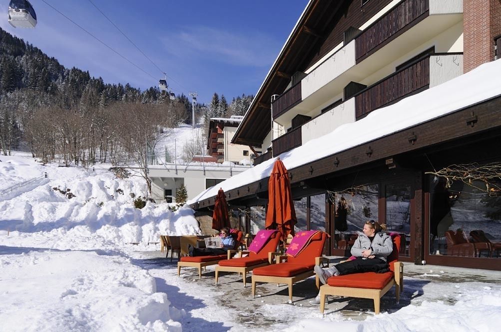 A ski resort with outdoor seating and a view of the snowy mountain.