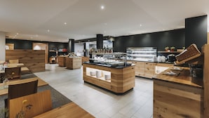 Um restaurante moderno com mobiliário de madeira, um balcão central com pratos e um esquema de cores preto e branco.