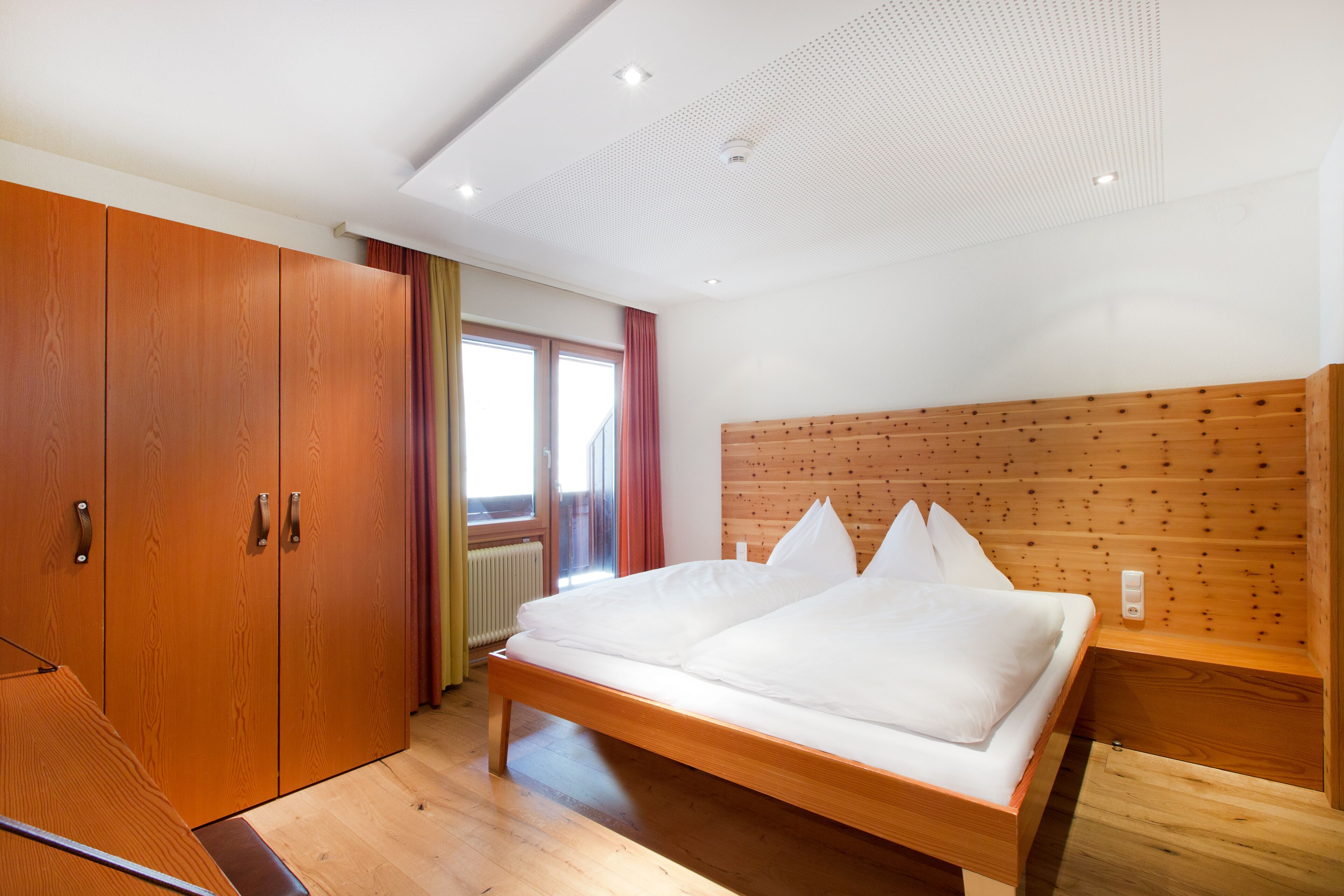 Un dormitorio con una cama de madera, un armario y cabecera de madera.