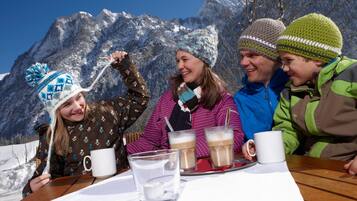 A group of people sitting at a wooden table outdoors with a mountain backdrop.