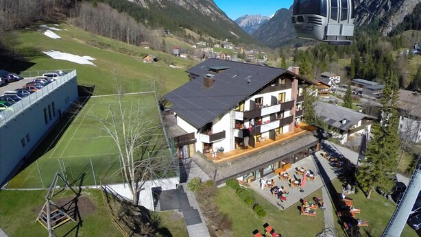 Um hotel de montanha com um teleférico, área de estar ao ar livre e vista das montanhas ao redor.