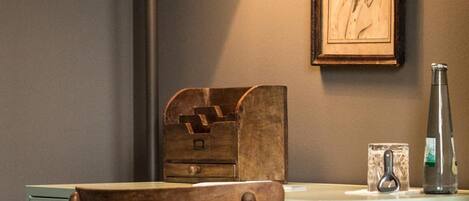 Un bureau avec une chaise, une lampe, un portrait encadré et une bouteille posée sur le bureau.