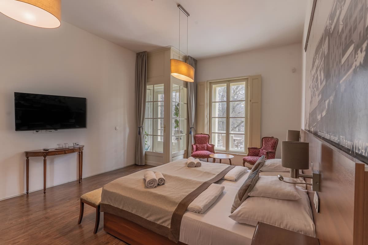 A hotel room with two beds, a television, a table with a lamp, and a chair.