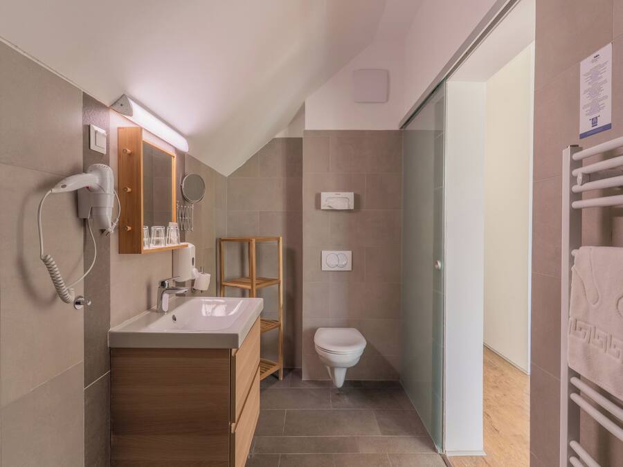 Un baño moderno con secador incorporado, tocador de madera, cabina de ducha con mampara de vidrio y barra para toallas.