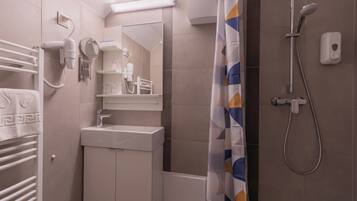 A bathroom with a shower, a sink, a hairdryer, and a towel rack.