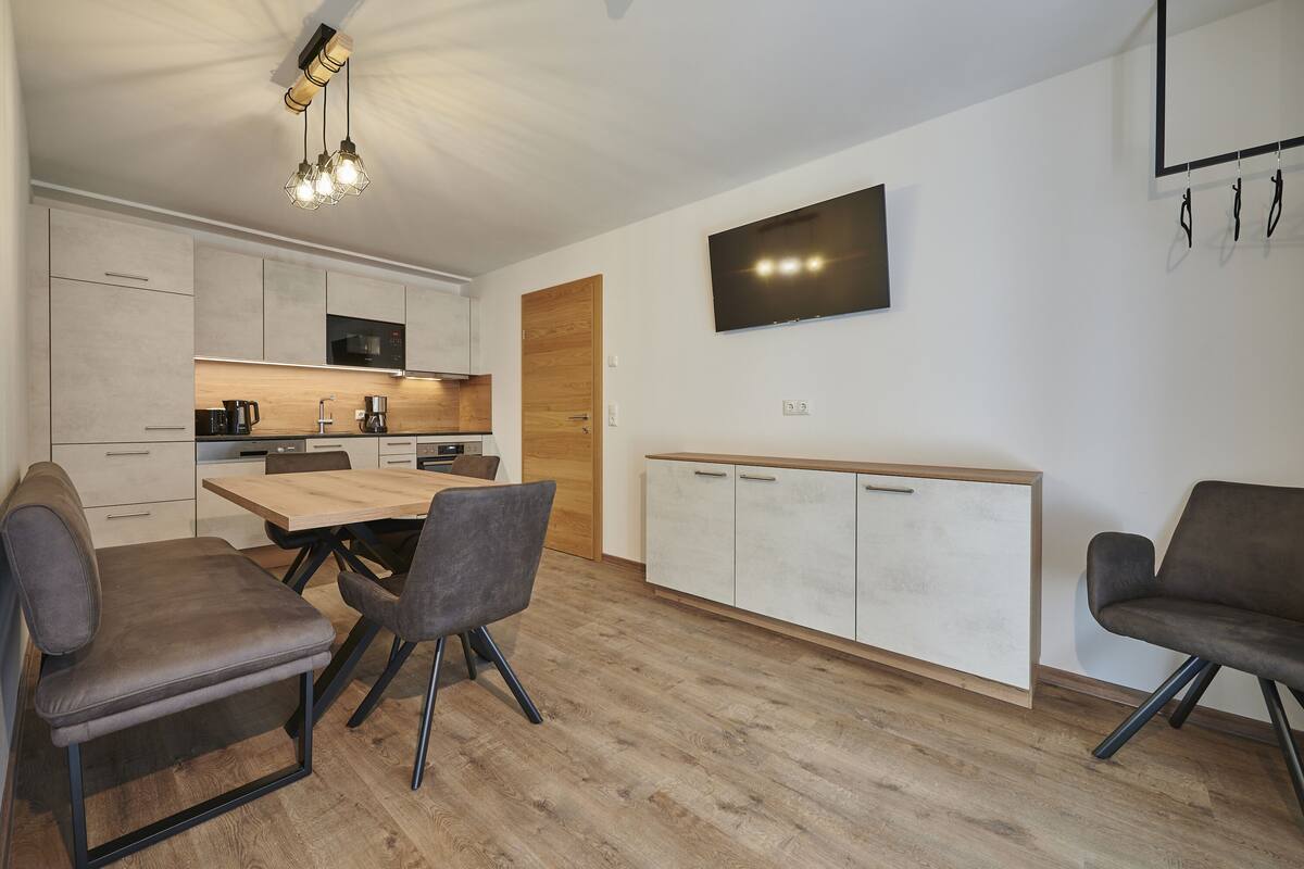 Una cocina moderna con comedor, armarios de madera, televisor de pantalla plana y una zona de estar.