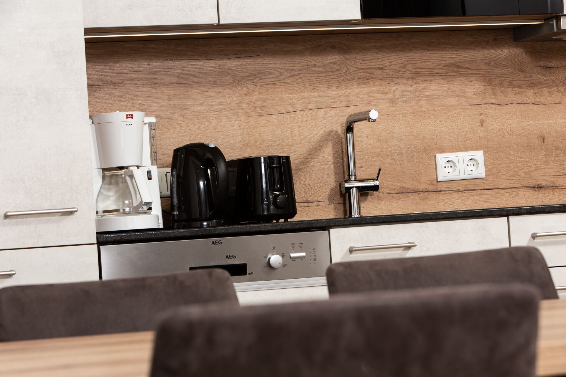 A kitchenette with a coffee maker, a toaster, and a built-in oven.