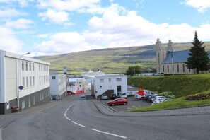 A street view with a building, parked cars, and a hill in the background. - K16 apartments (Akureyri)