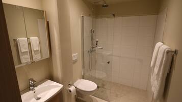 A modern bathroom with a sink, toilet, and glass-enclosed shower.