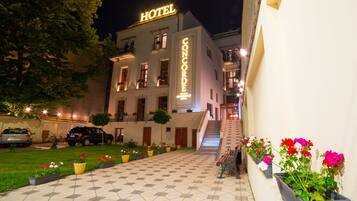 Un hotel con un patio empedrado, una escalera que conduce a la entrada y macetas con flores a lo largo del camino.