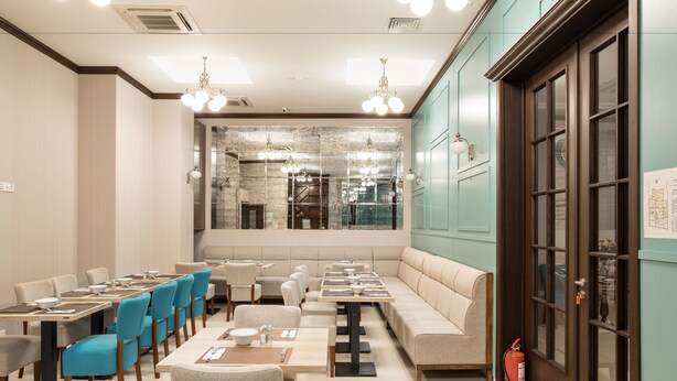 Un restaurant avec un long comptoir, des chaises bleues et une grande fenêtre.
