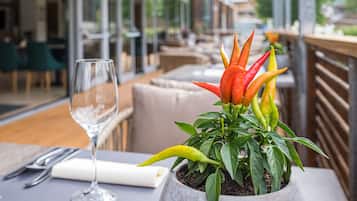 A dining table with a potted plant, a wine glass, and a napkin.