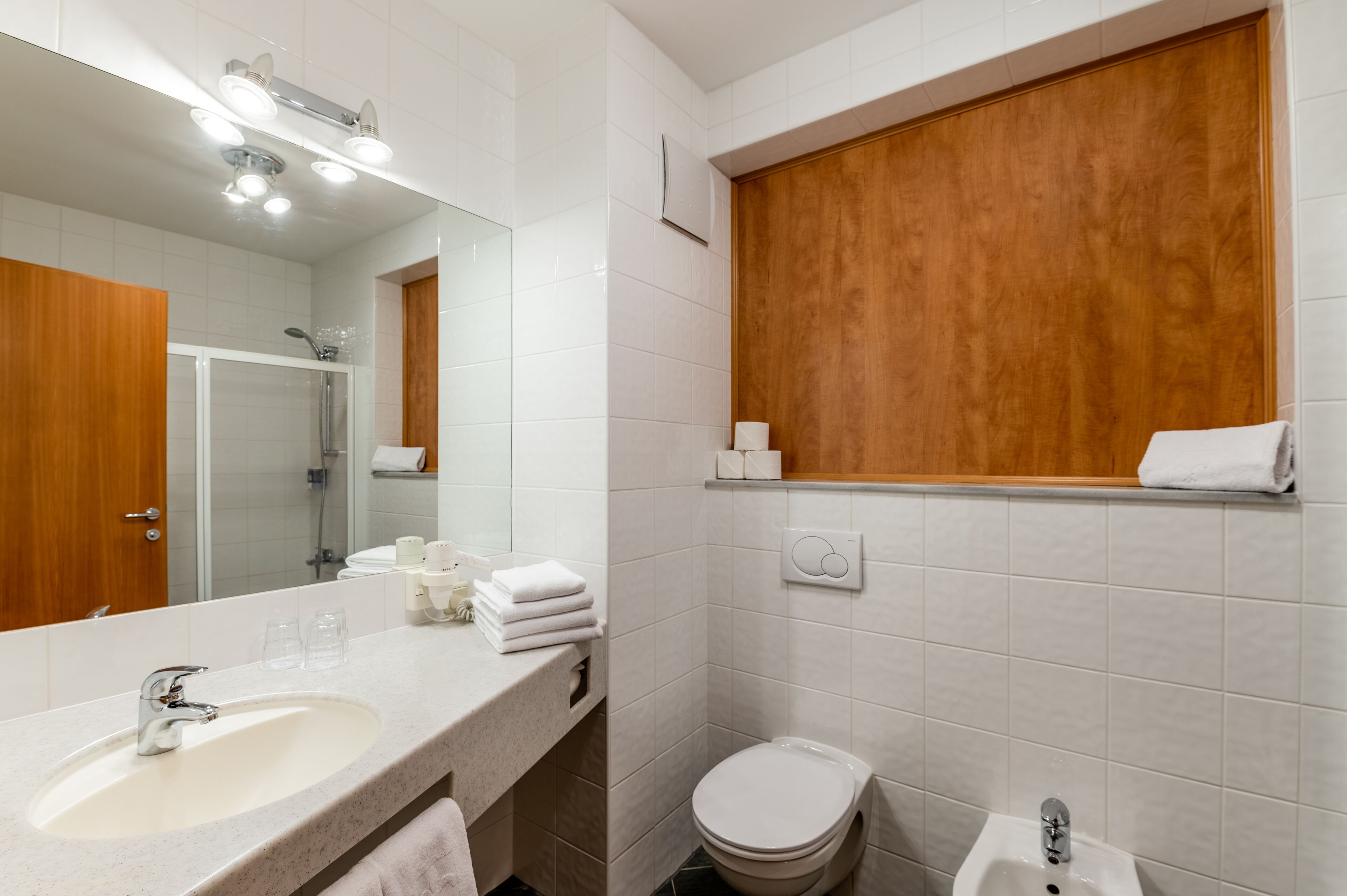 Une salle de bain moderne avec un grand miroir, un lavabo, des toilettes et un bidet.