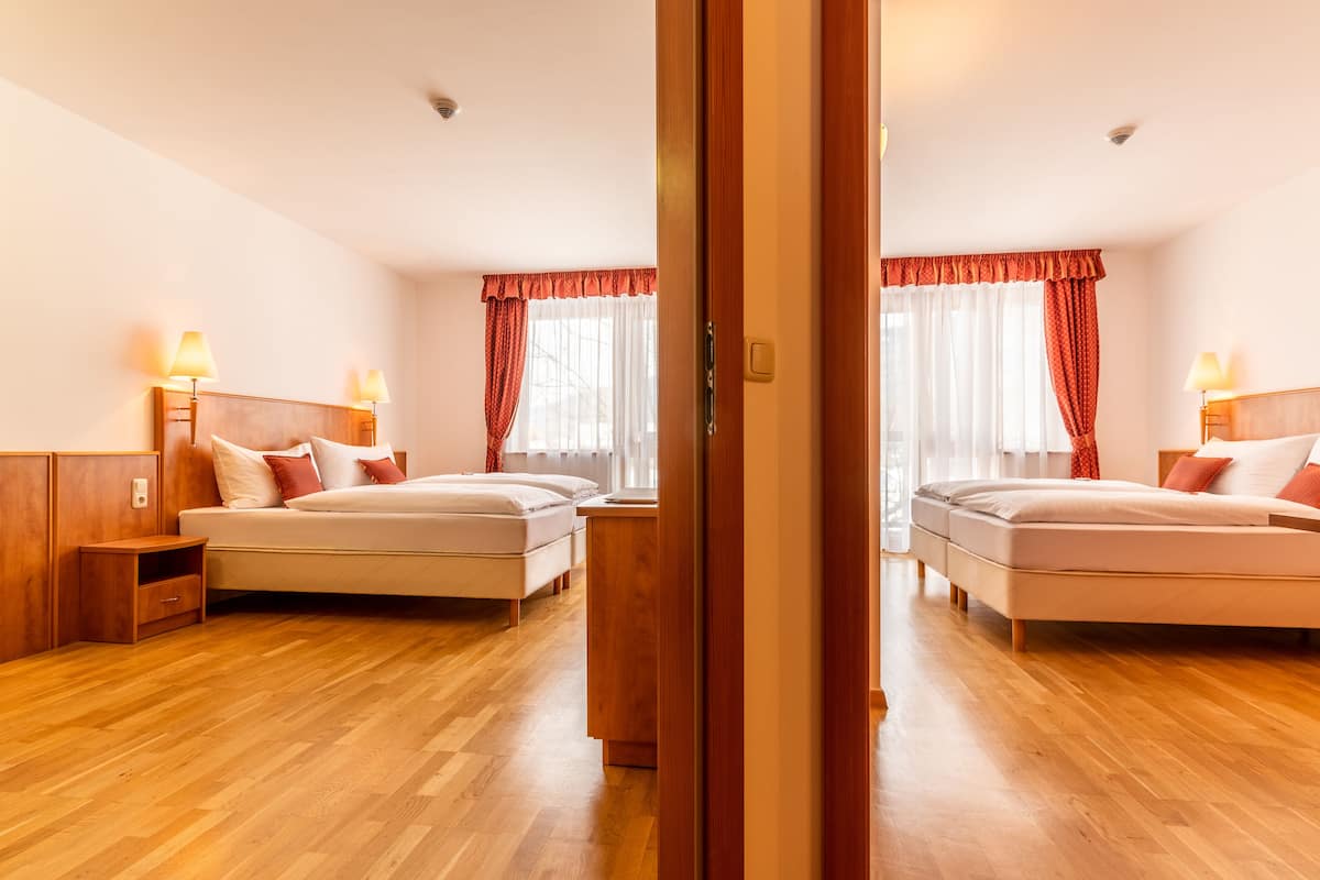 Quarto de hotel com duas camas, piso de madeira e cabeceira de madeira.