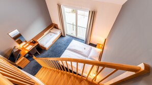 A hotel room with a wooden staircase, two beds, a desk with a computer, and a large window with curtains. - Club Hotel am Kreischberg (Sankt Georgen am Kreischberg)