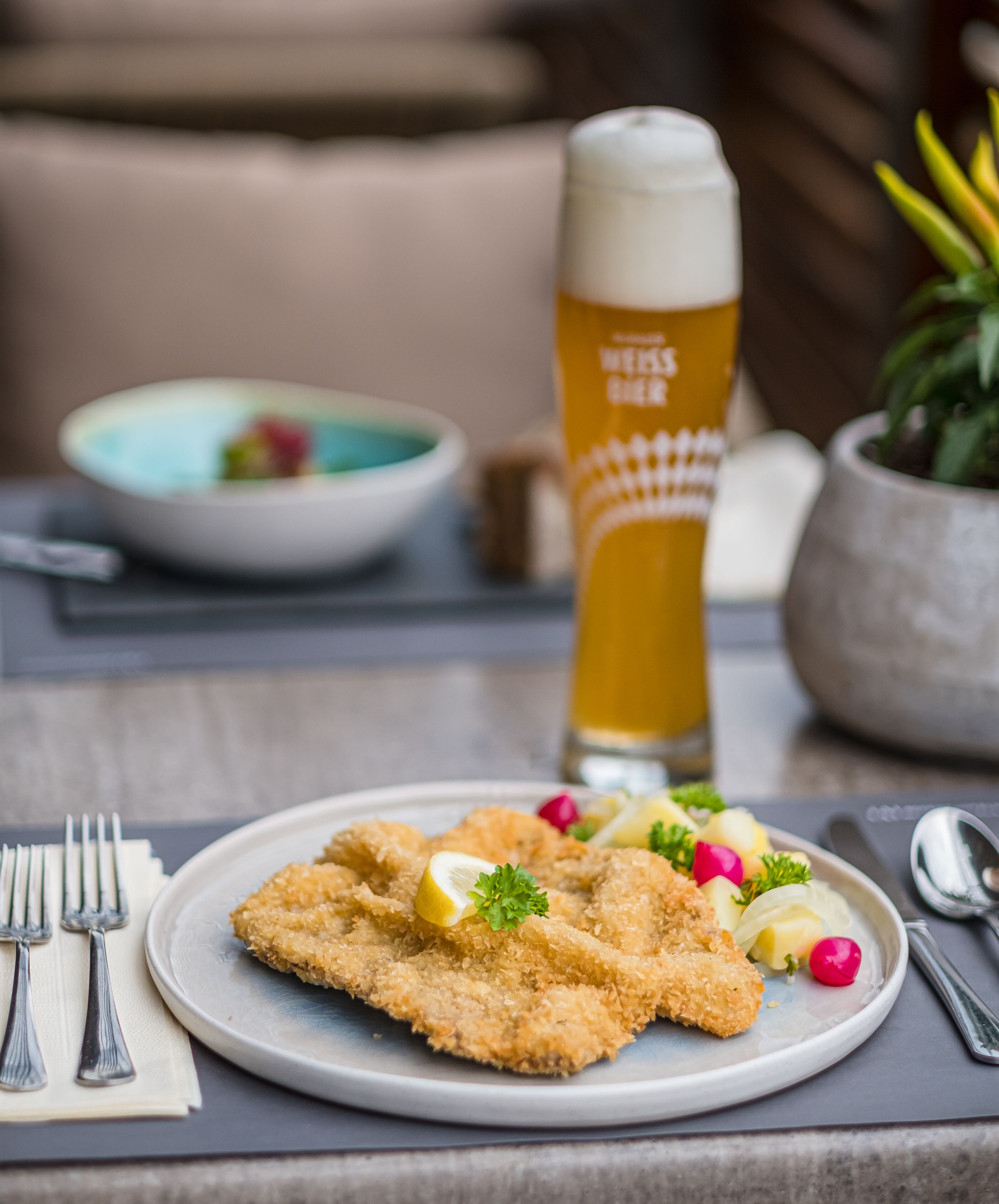 Une assiette de filets de poisson panés, garnis d’une tranche de citron et de persil, un verre de bière et un saladier de salade.