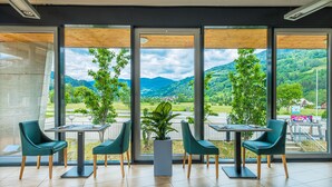 A modern indoor seating area with large windows offering a view of a mountainous landscape. - Club Hotel am Kreischberg (Sankt Georgen am Kreischberg)