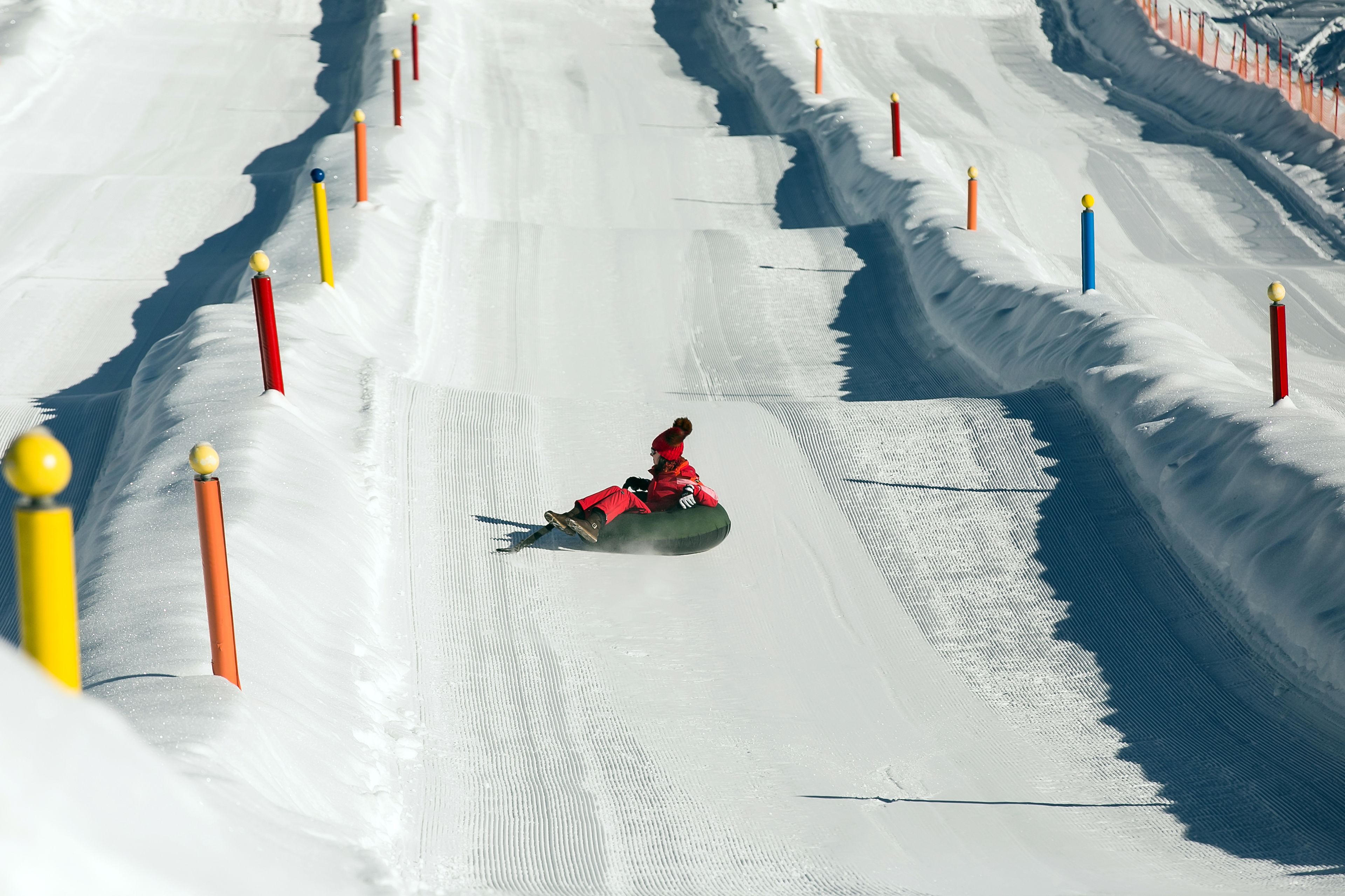 A person sliding down a snowy slope with colorful poles marking the path.