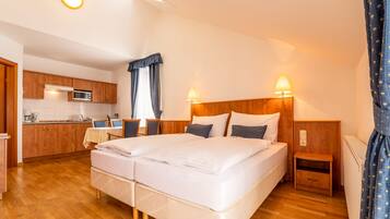 Et hotelværelse med dobbeltseng, sengeborde, et lille skrivebord med stol, et tekøkken og et badeværelse.
