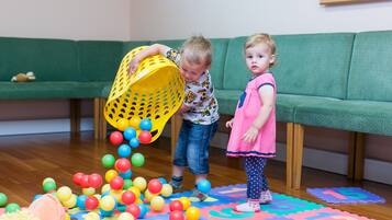 A child playing with colorful balls on a mat, with a green sofa in the background.