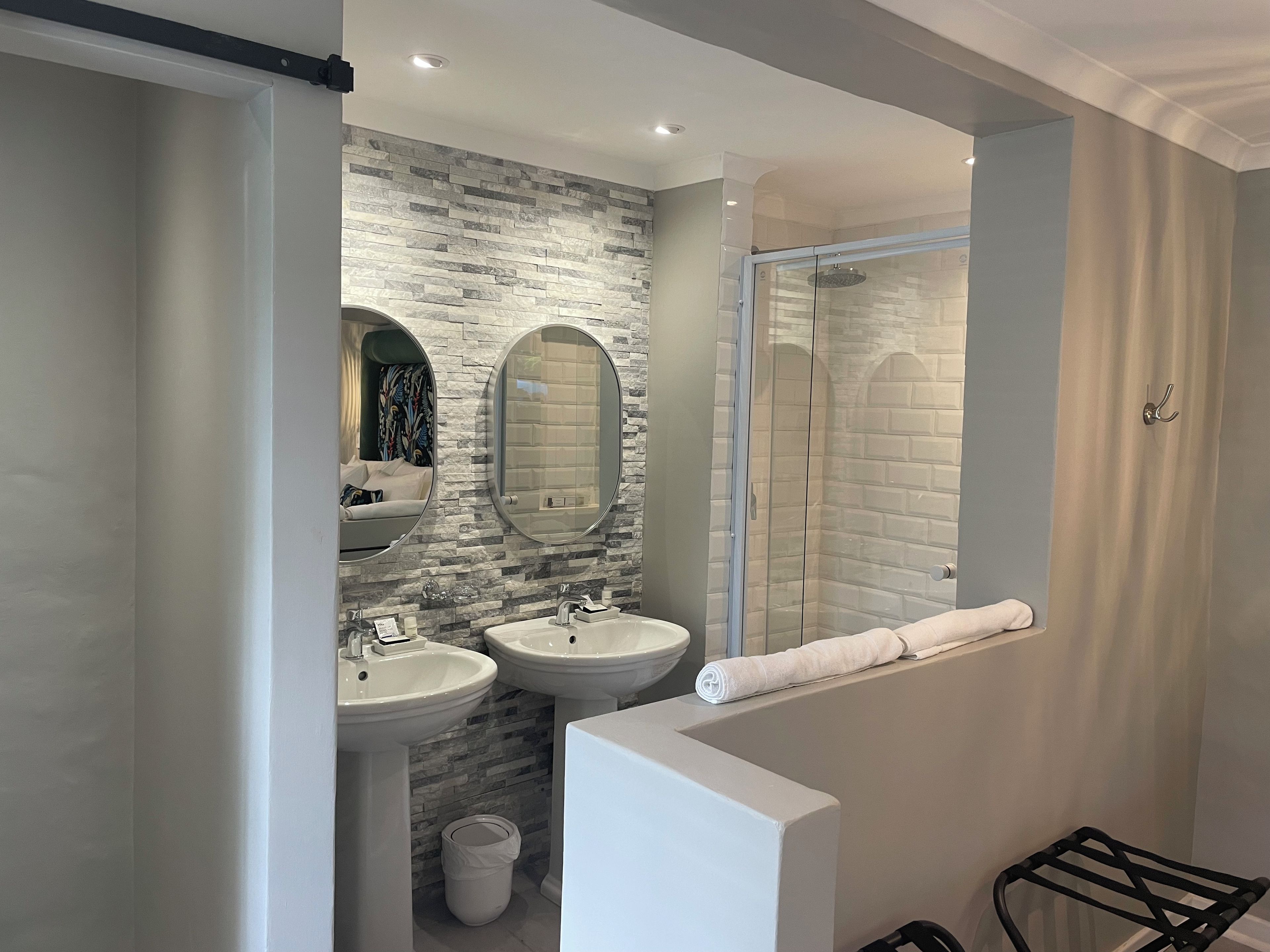 A modern bathroom with two sinks, a shower, and a glass-enclosed shower area.