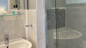 Casa de banho moderna com cabine de duche em vidro, lavatório branco e zona de duche com azulejos.