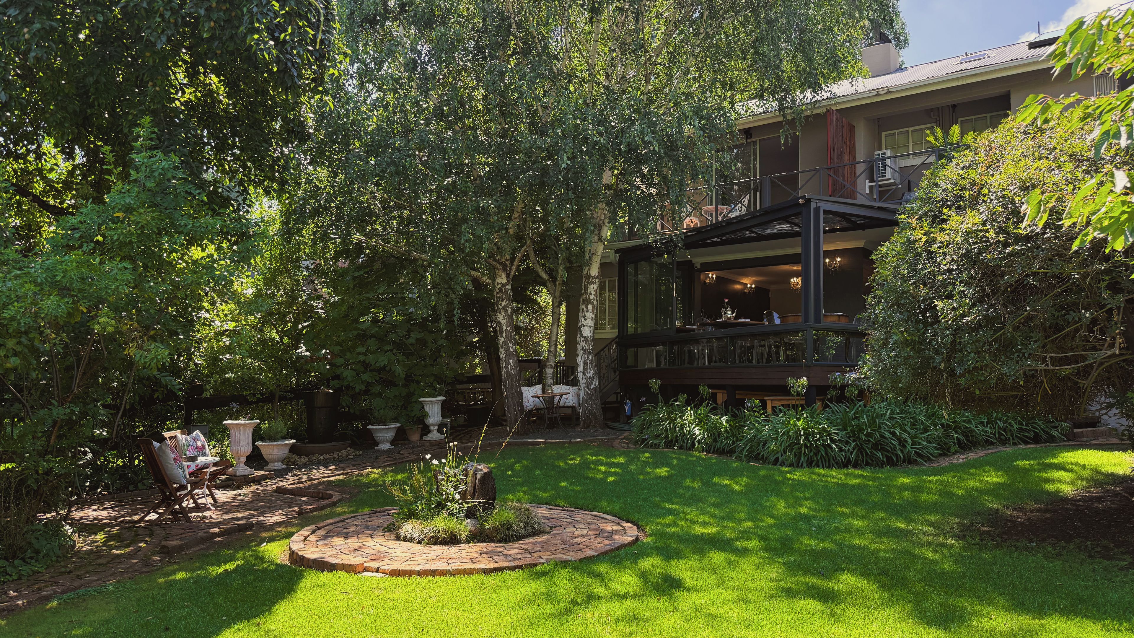 Un jardin luxuriant agrémenté d’un patio, d’un chemin de pierre et d’un espace aménagé pour les repas.