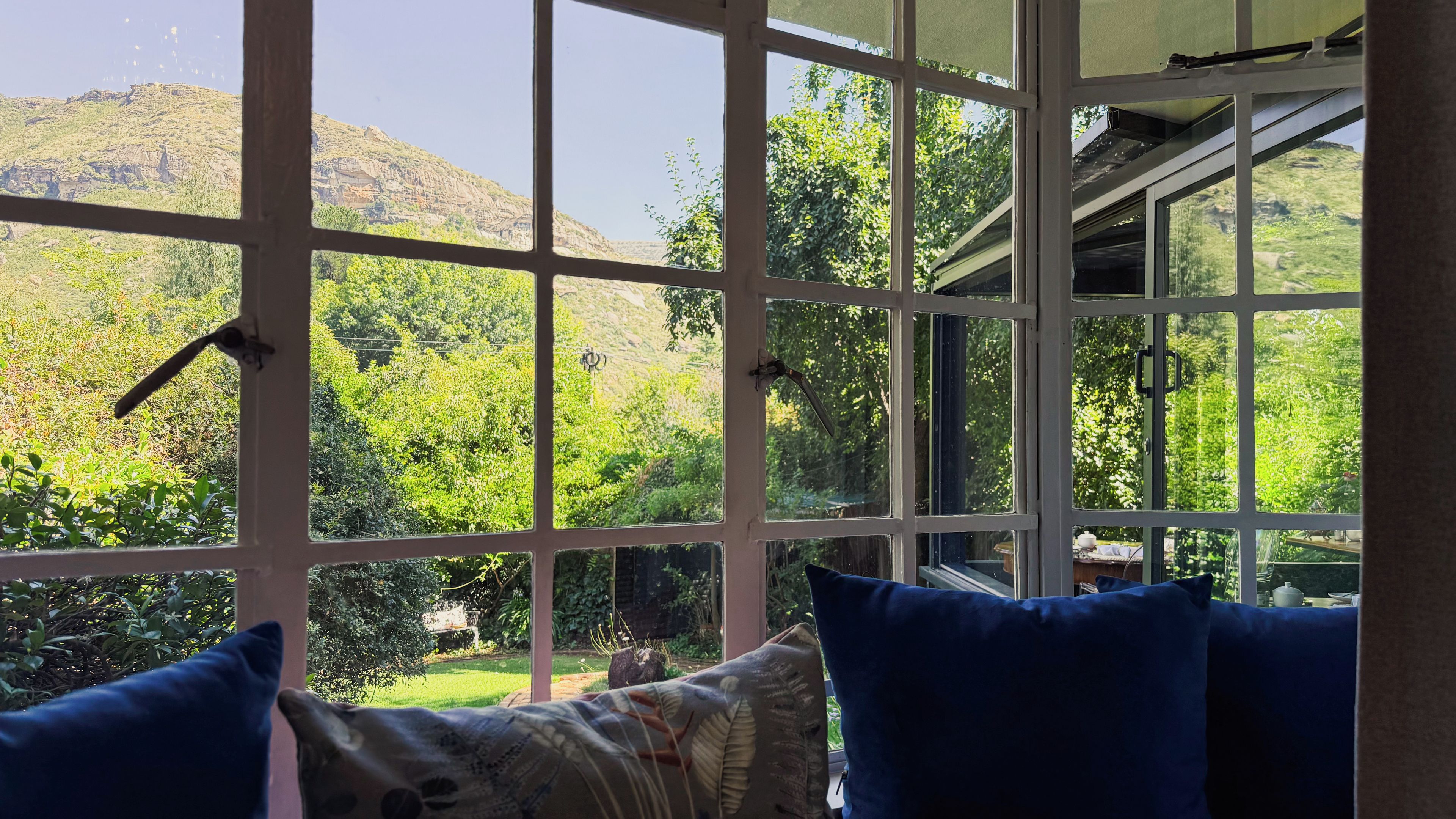 Une pièce dotée d’une grande fenêtre donnant sur un jardin luxuriant et une montagne.