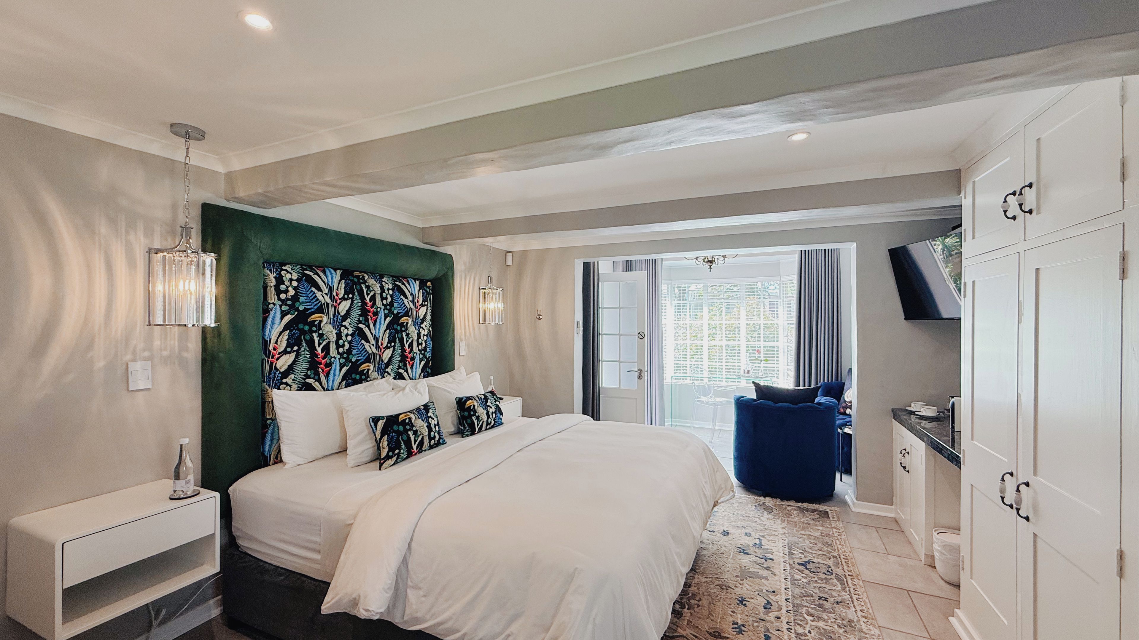 A modern bedroom with a large bed, a television, and a view of the outdoors.