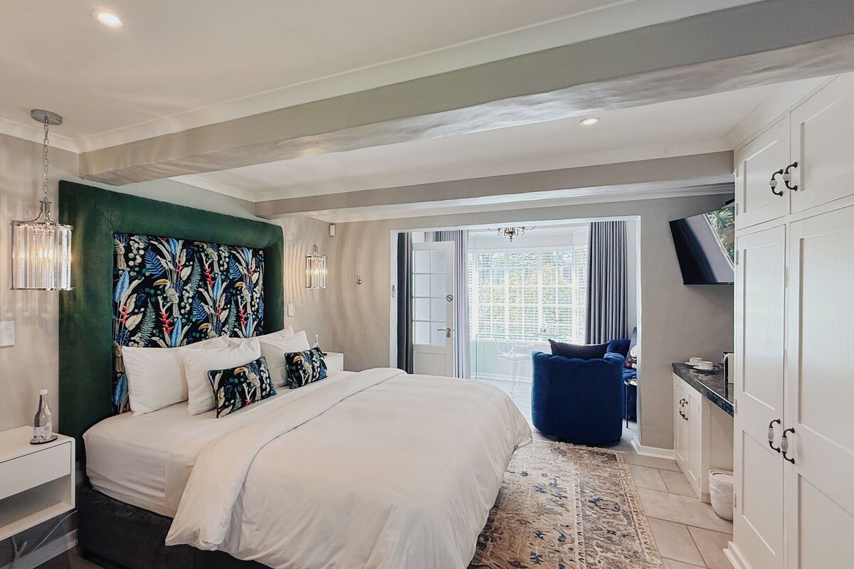 A modern bedroom with a large bed, a television, and a view of the outdoors.