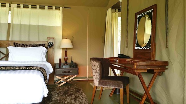 A hotel room with a bed, a desk, a chair, a lamp, and a mirror.