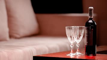 Una botella de vino y dos copas sobre una mesa de madera en una habitación de hotel.