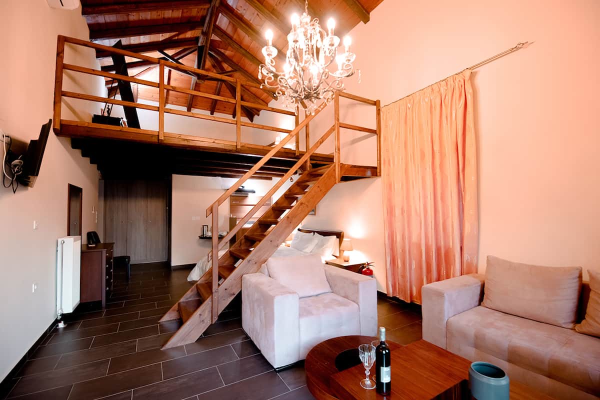 A spacious living area with a wooden staircase, a white sofa, a wooden coffee table, and a chandelier.