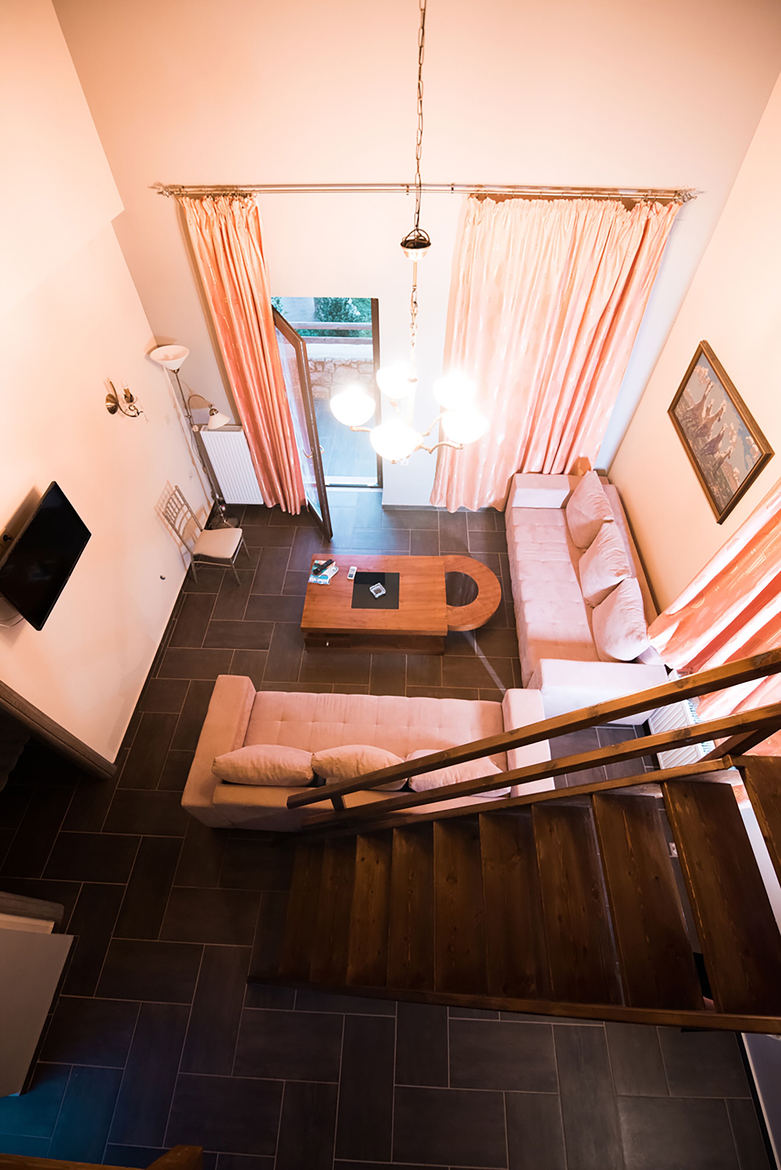 Un salon moderne avec un canapé d’angle, une table basse en bois et un escalier menant à un autre niveau.